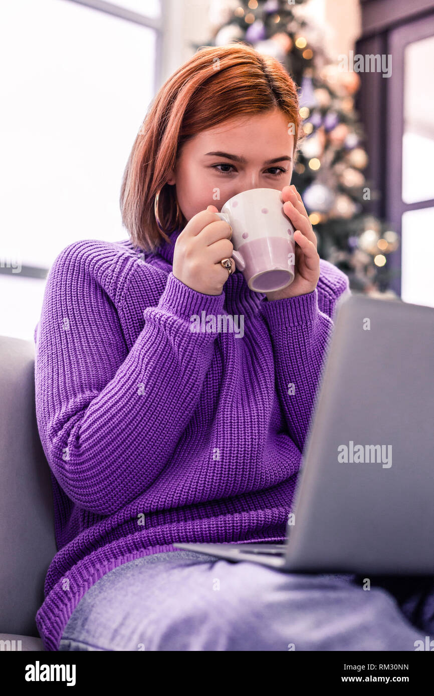 Guapa joven pelirroja chica radiante en un suéter violeta tomando té  Fotografía de stock - Alamy