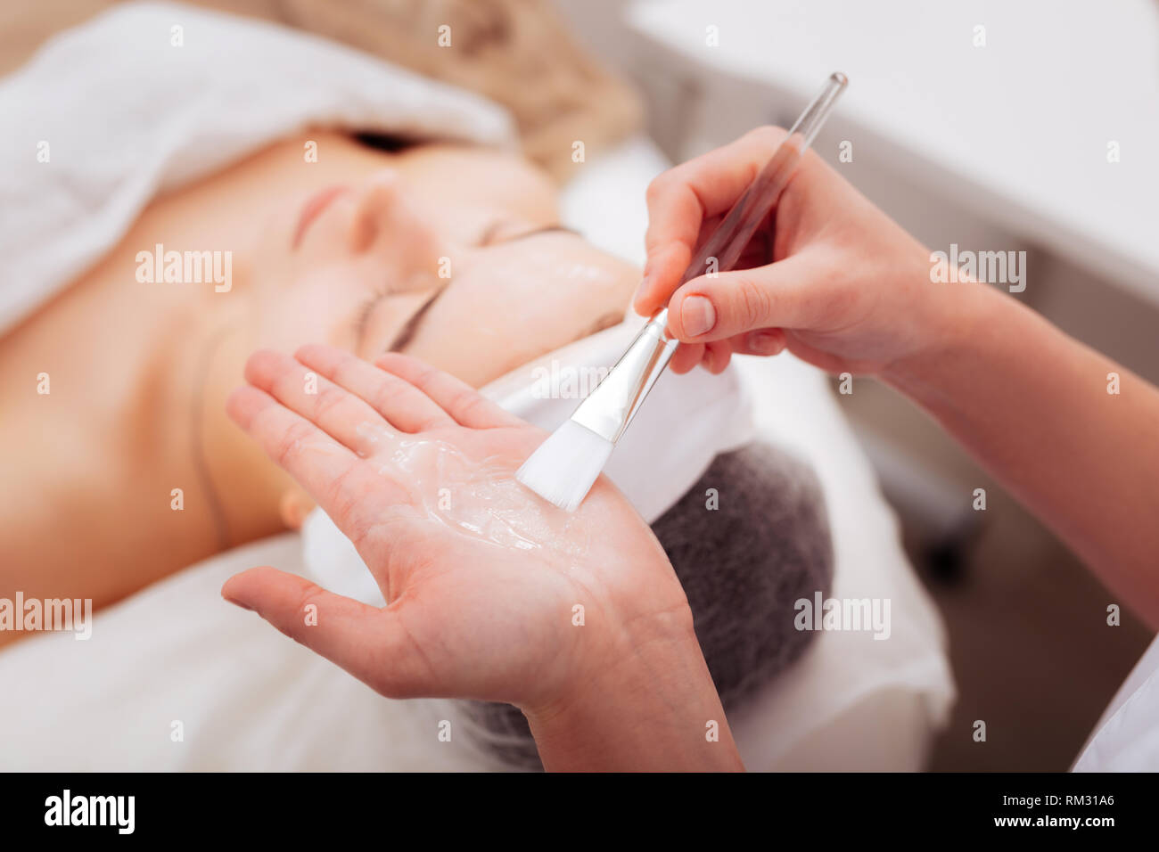 Limpieza facial profunda de la cara de una mujer con las manos y una  cuchara de un esteticista en guantes. En el salón con una toalla blanca.  Cosmetólogo usando Fotografía de stock 