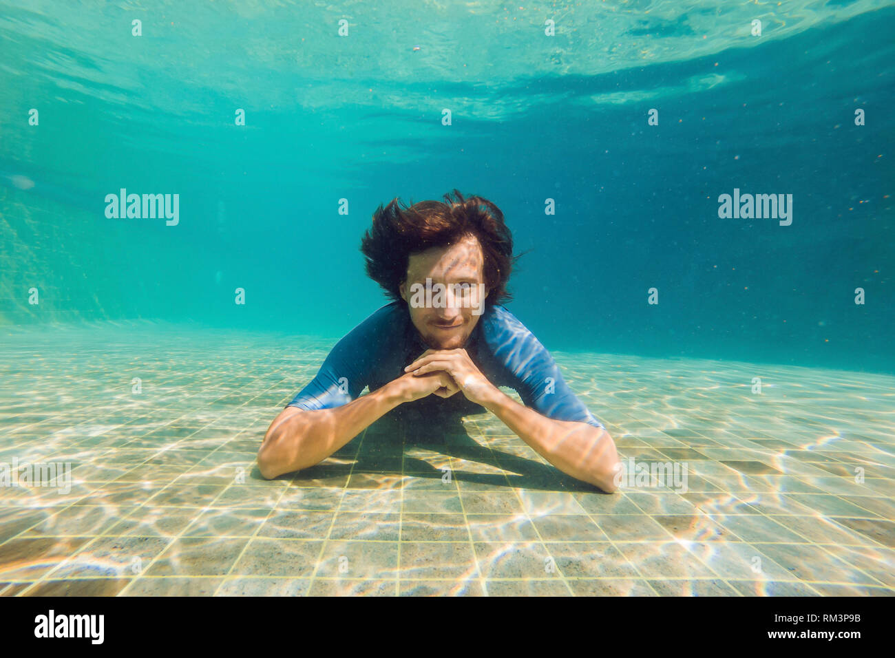 El hombre en el fondo de la piscina, bucea bajo el agua Fotografía de