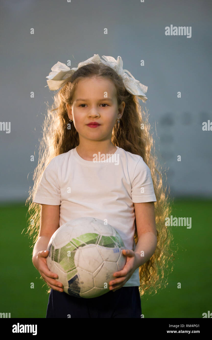 contento pequeño niña sonrisas con fútbol pelota en manos 27856585
