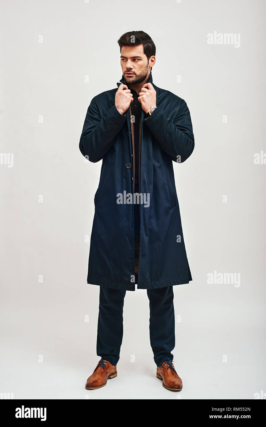 Retrato de cuerpo entero de morena elegante hombre vestido con pantalones  azules, chaqueta marrón y permanente de Blue Coat y apartar la mirada  aislada sobre fondo blanco Fotografía de stock - Alamy