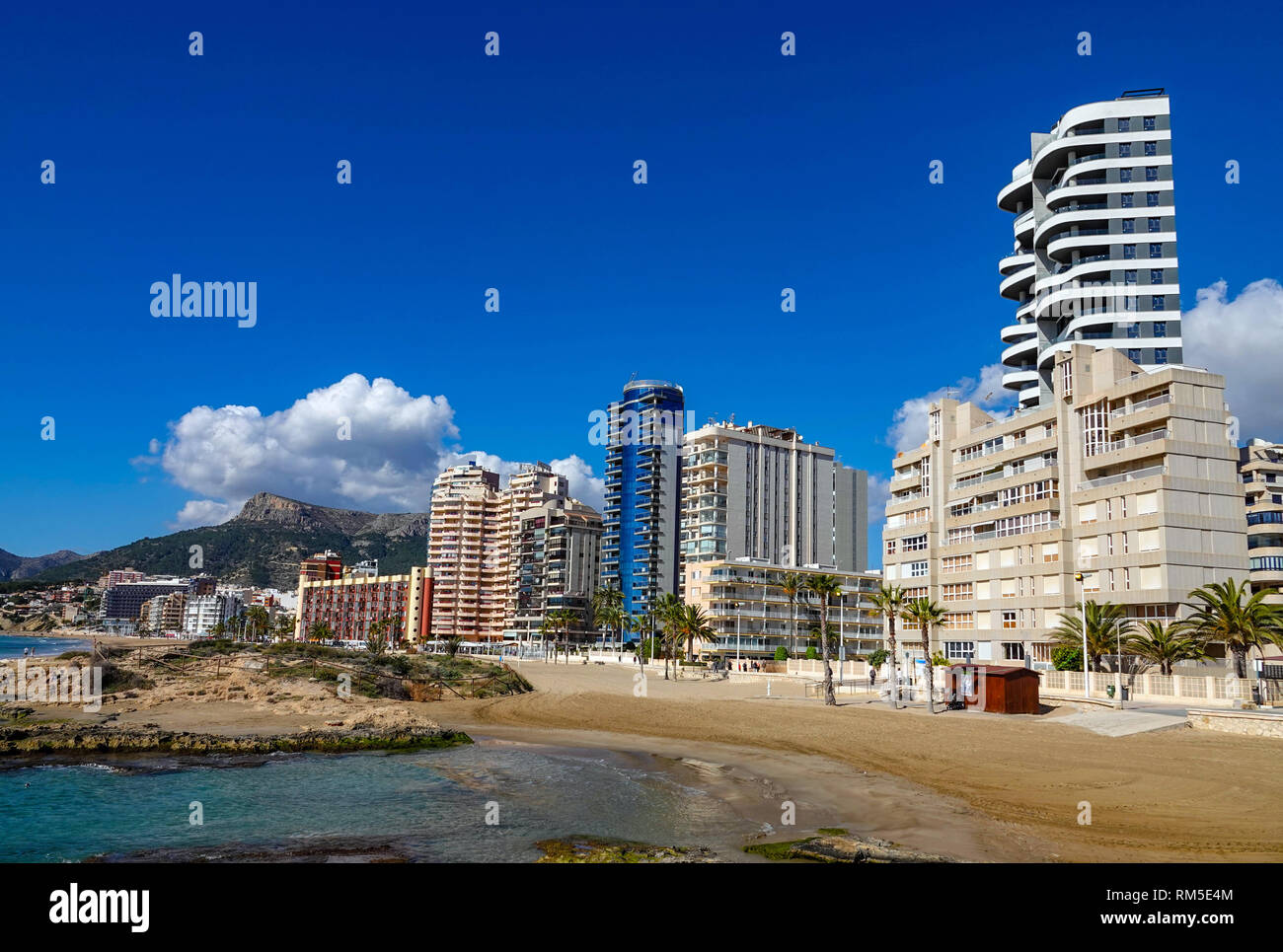 Mar azul, playa y bloques de apartamentos en el centro turístico popular española de Calpe, provincia de Valencia, España Foto de stock