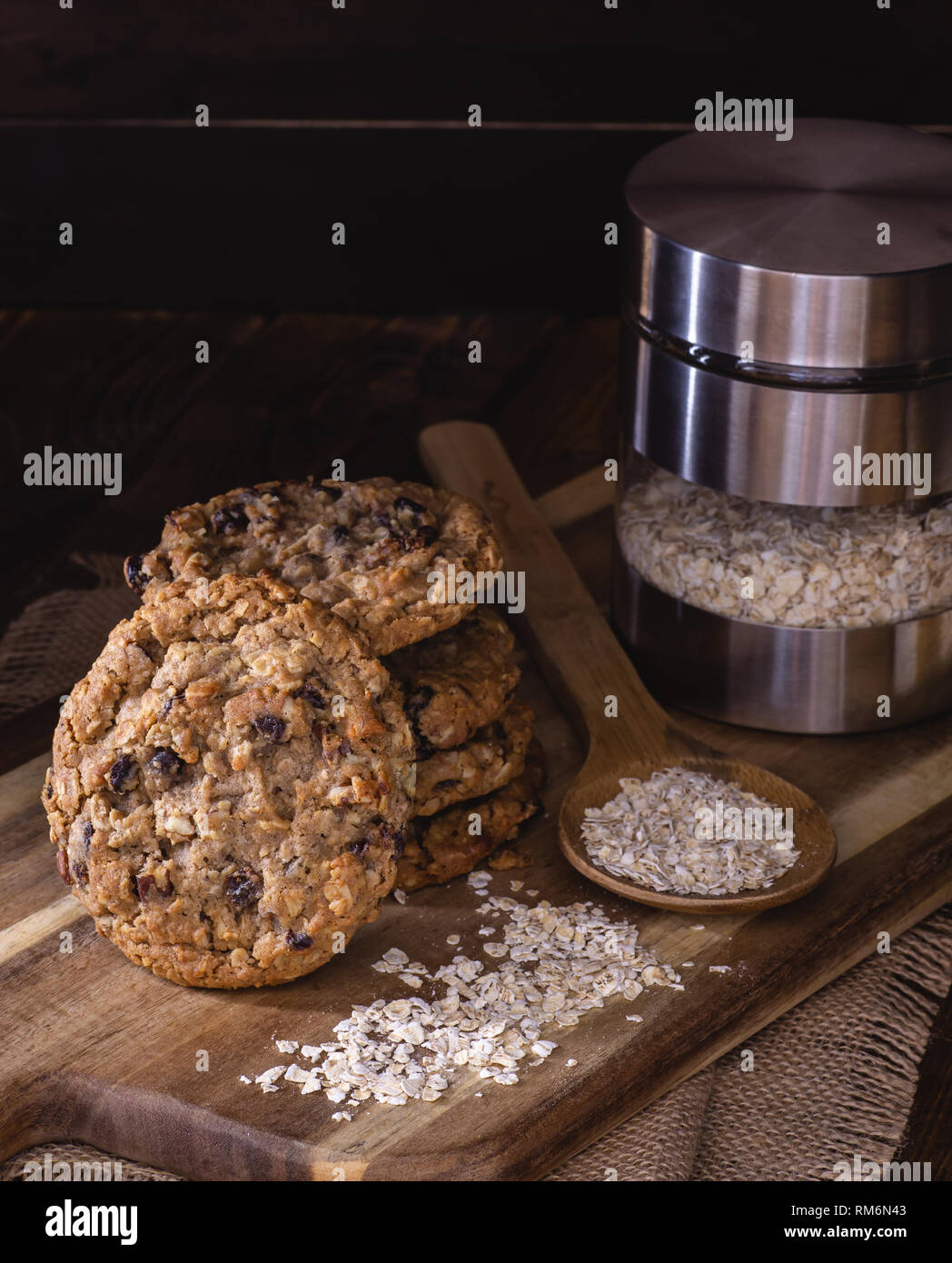 Pila de avena y avena cookies tuerca pasas copos sobre una placa de madera en un oscuro rústico Foto de stock