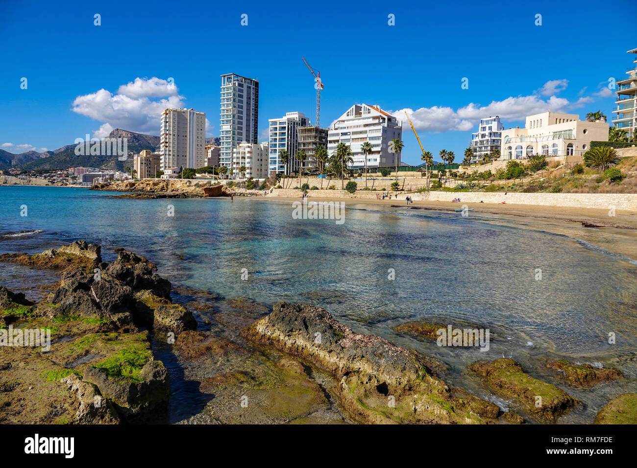 Mar azul, playa y bloques de apartamentos en el centro turístico popular española de Calpe, provincia de Valencia, España Foto de stock