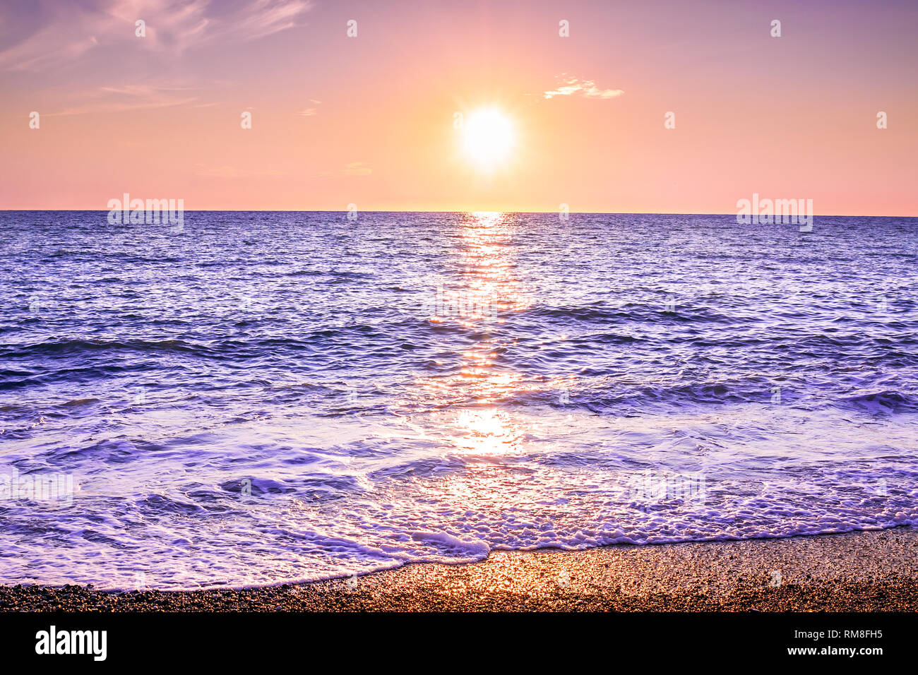 Paisaje púrpura con el mar y la puesta de sol. sol vespertino sobre el océano. El hermoso paisaje con puesta de sol sobre el mar vista panorámica Foto de stock