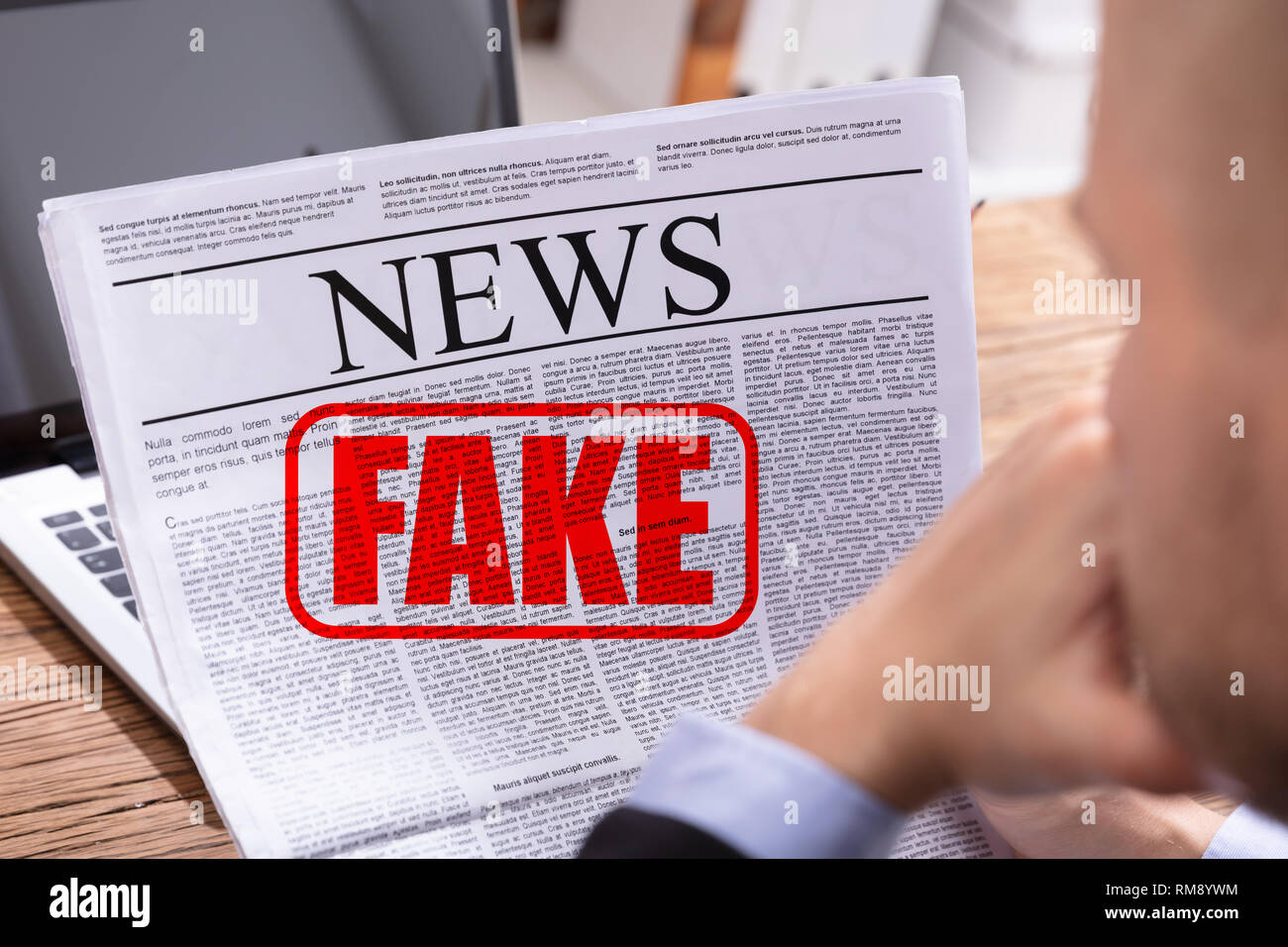 Hombre leyendo noticias falsas en el periódico sobre la mesa Foto de stock