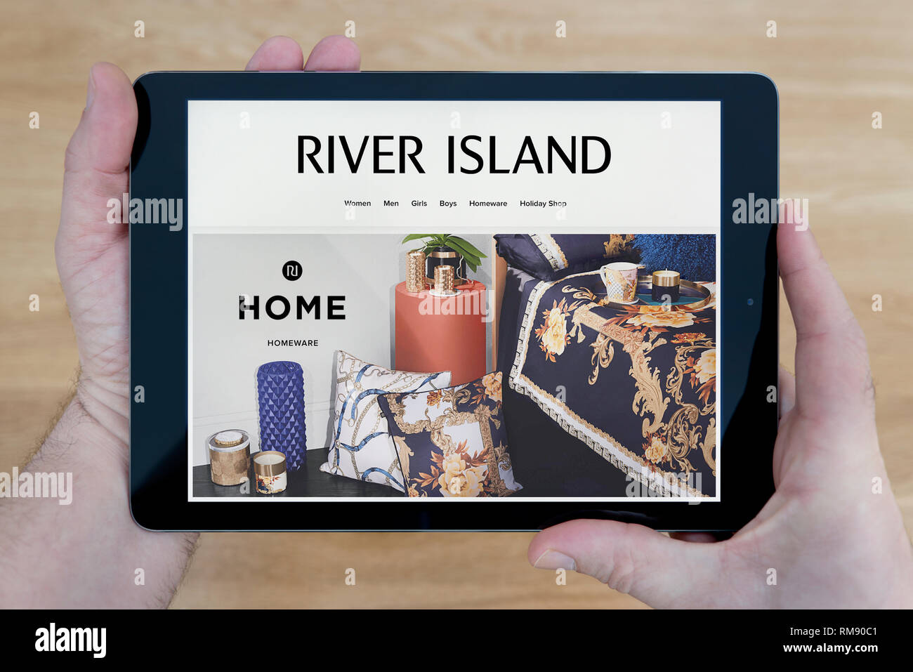 Un hombre que mira a la isla fluvial website en su iPad dispositivo tablet, disparó contra una mesa de madera de fondo (sólo para uso editorial). Foto de stock