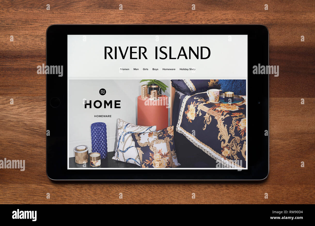 El sitio web de River Island es visto en un iPad, que descansa sobre una mesa de madera (uso Editorial solamente). Foto de stock