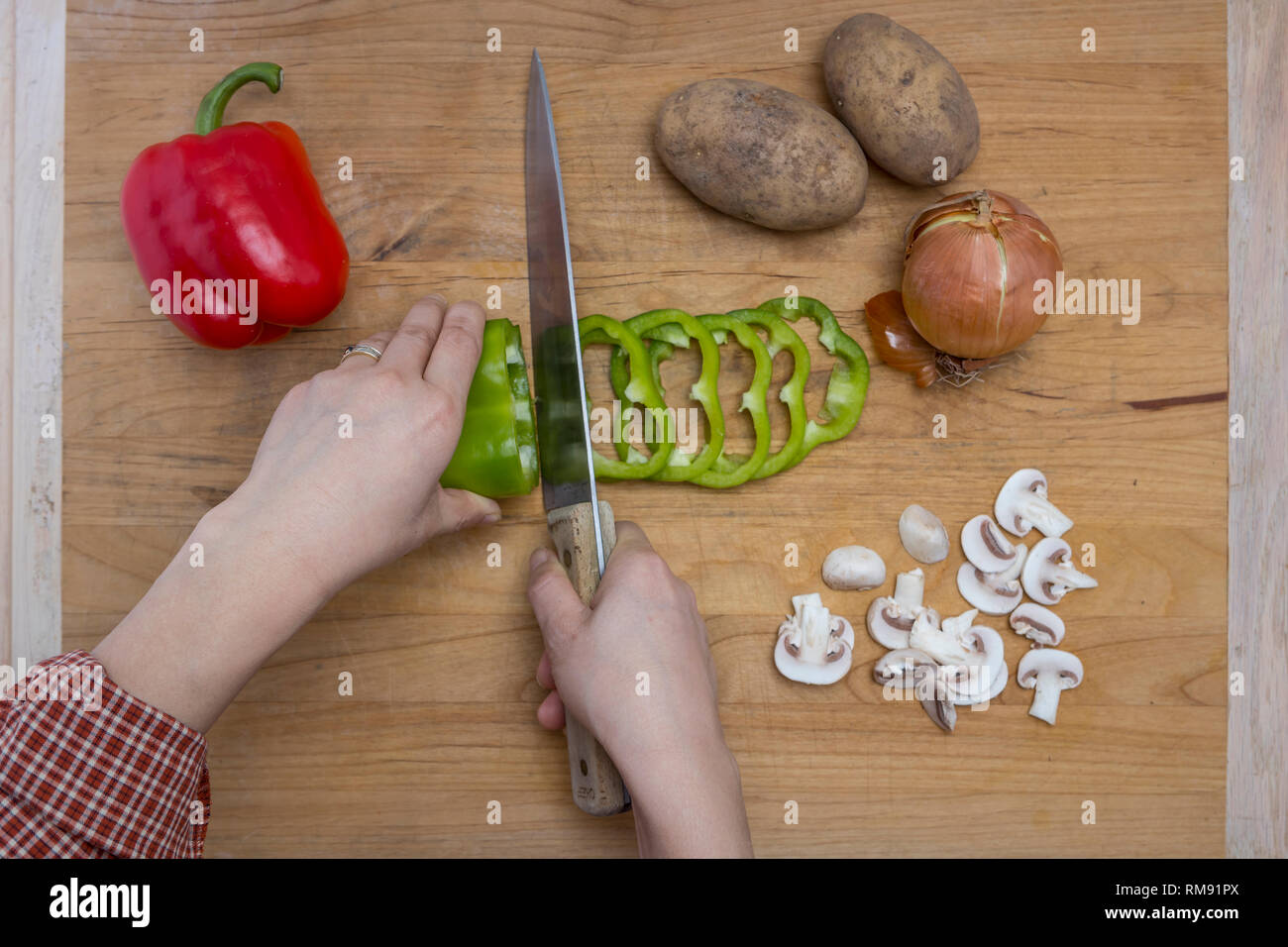 El acto de cortar verduras surtidas en una tabla para cortar. Foto de stock