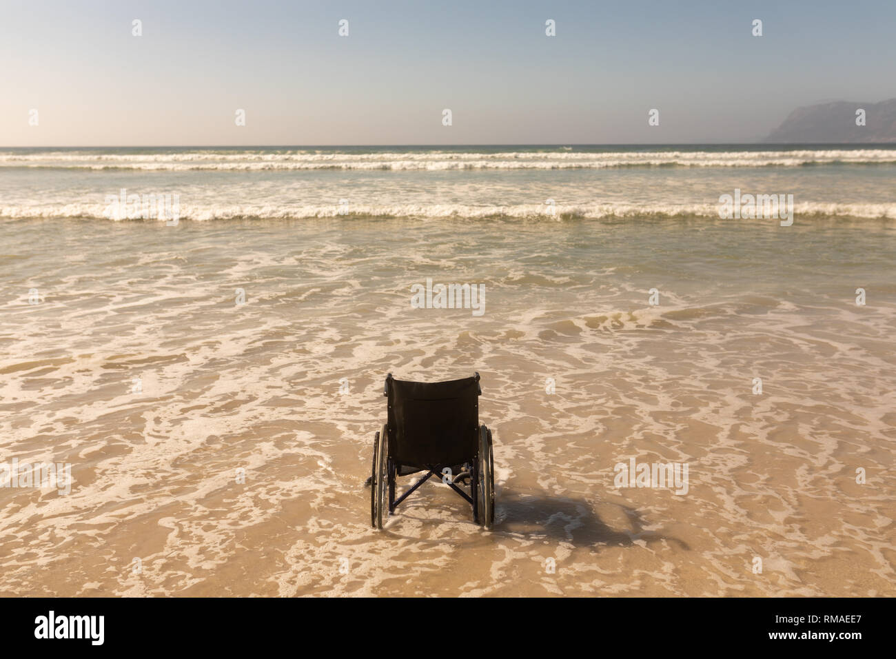 Silla de ruedas a la orilla del mar, en la playa Foto de stock