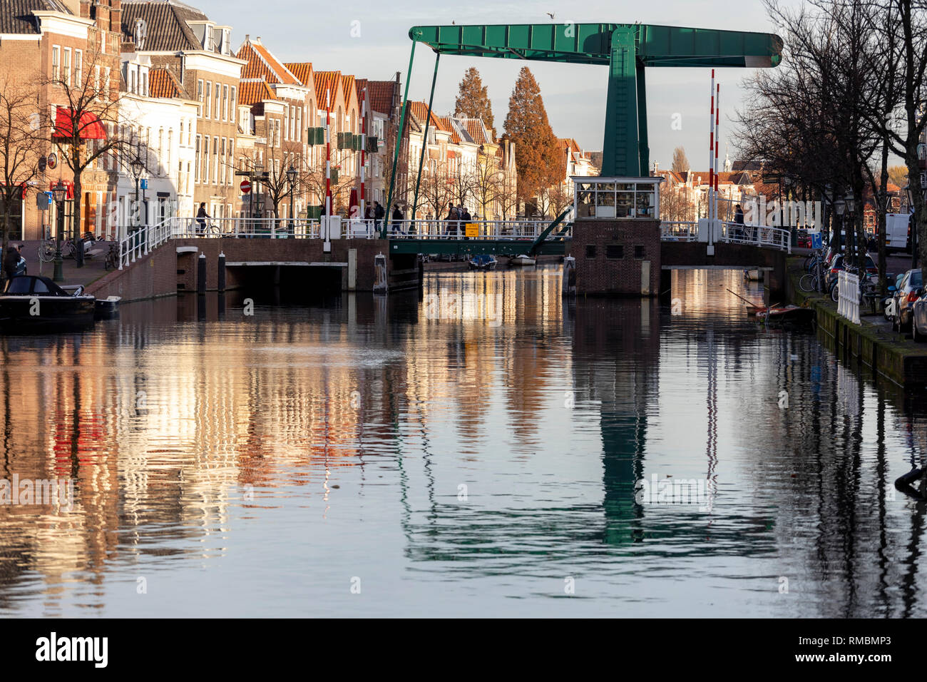 Puente levadizo típico holandés en la ciudad de Leiden se refleja en el canal al atardecer con casas de canal estático en el fondo Foto de stock