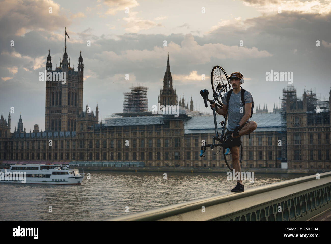 Londres, Reino Unido - abril de 2018. Un joven acrobat con una bicicleta en la barandilla del puente Westminster. Foto de stock