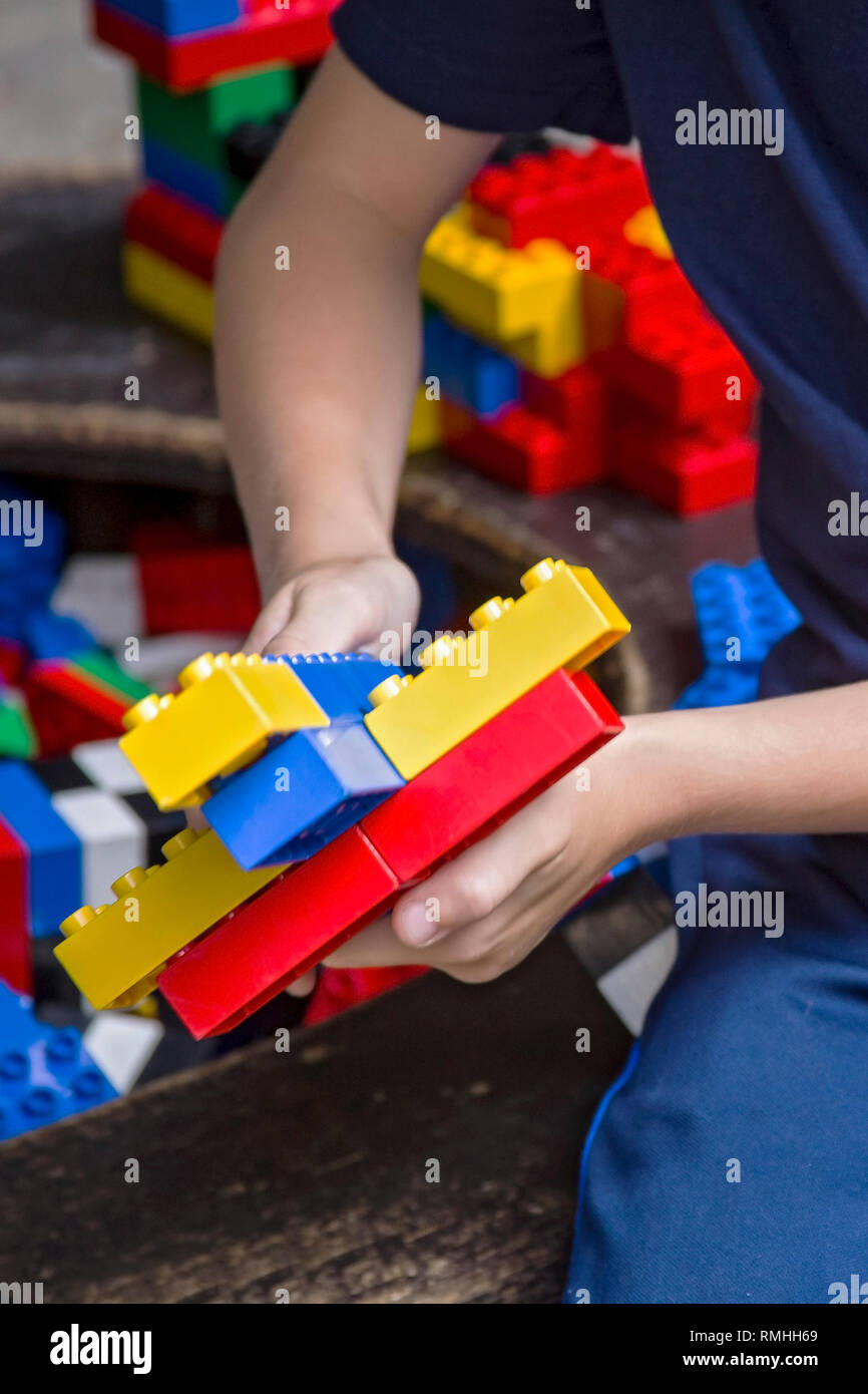 Acercamiento de las manos del niño con coloridos bricksof un kit de plástico. Foto de stock