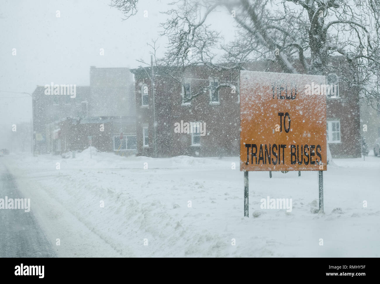 En Downie Street en Stratford, Ontario, vemos una señal de tráfico que nos pide a ceder a los autobuses de tránsito que salga de la terminal. Squall tormenta en invierno. Foto de stock