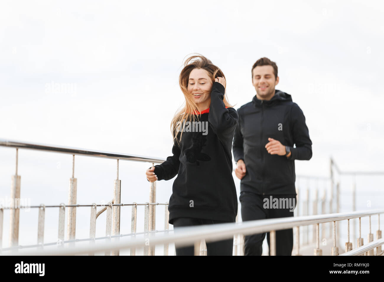 Sofisticado Unidad galope Imagen de la feliz pareja deportiva hombre y mujer ropa deportiva negra que  corre a lo largo del muelle en seaside Fotografía de stock - Alamy