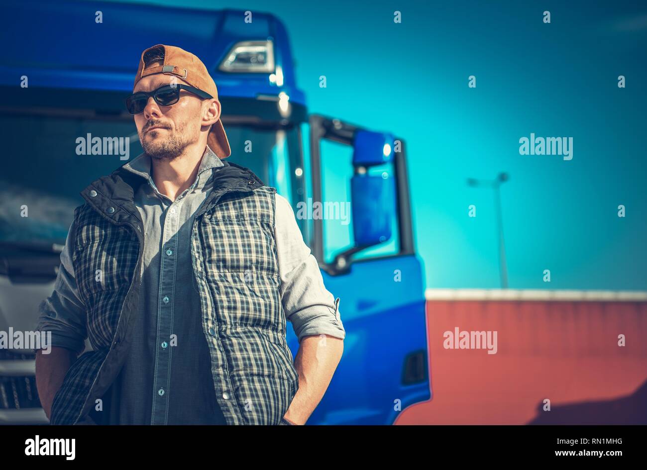 La conducción de camiones concepto empresarial. Camionero caucásica delante de su moderno semi azul. Foto de stock