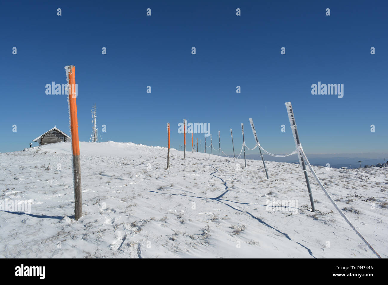 Pequeño weather shelter, antena y pilares con soga en la larga fila en la cima de la montaña, la asistencia necesaria a los esquiadores en invierno neblinoso días Foto de stock