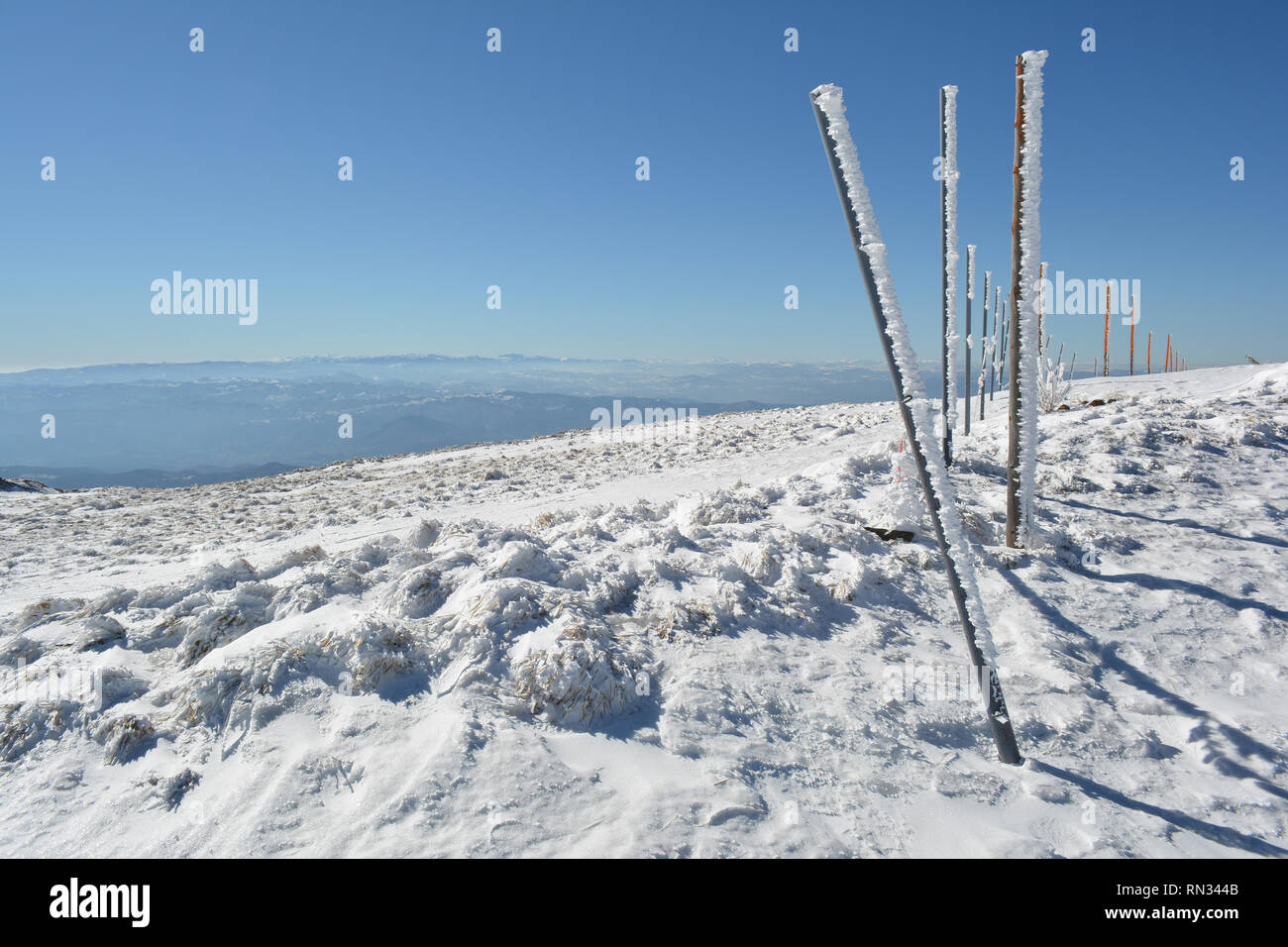 Hierro y pilares de madera cubierto con carámbanos en largas filas en la cima de la montaña, la asistencia necesaria a los esquiadores en invierno neblinoso días Foto de stock