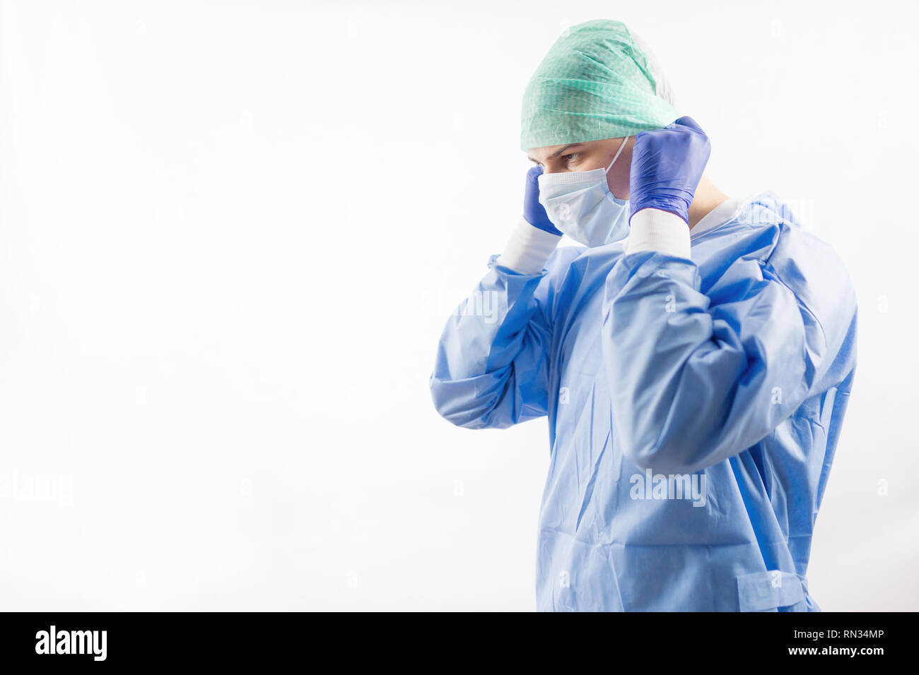 Médico cirujano guantes estériles en preparación para el funcionamiento en  el hospital. Él está usando la tapa quirúrgica y bata azul Fotografía de  stock - Alamy