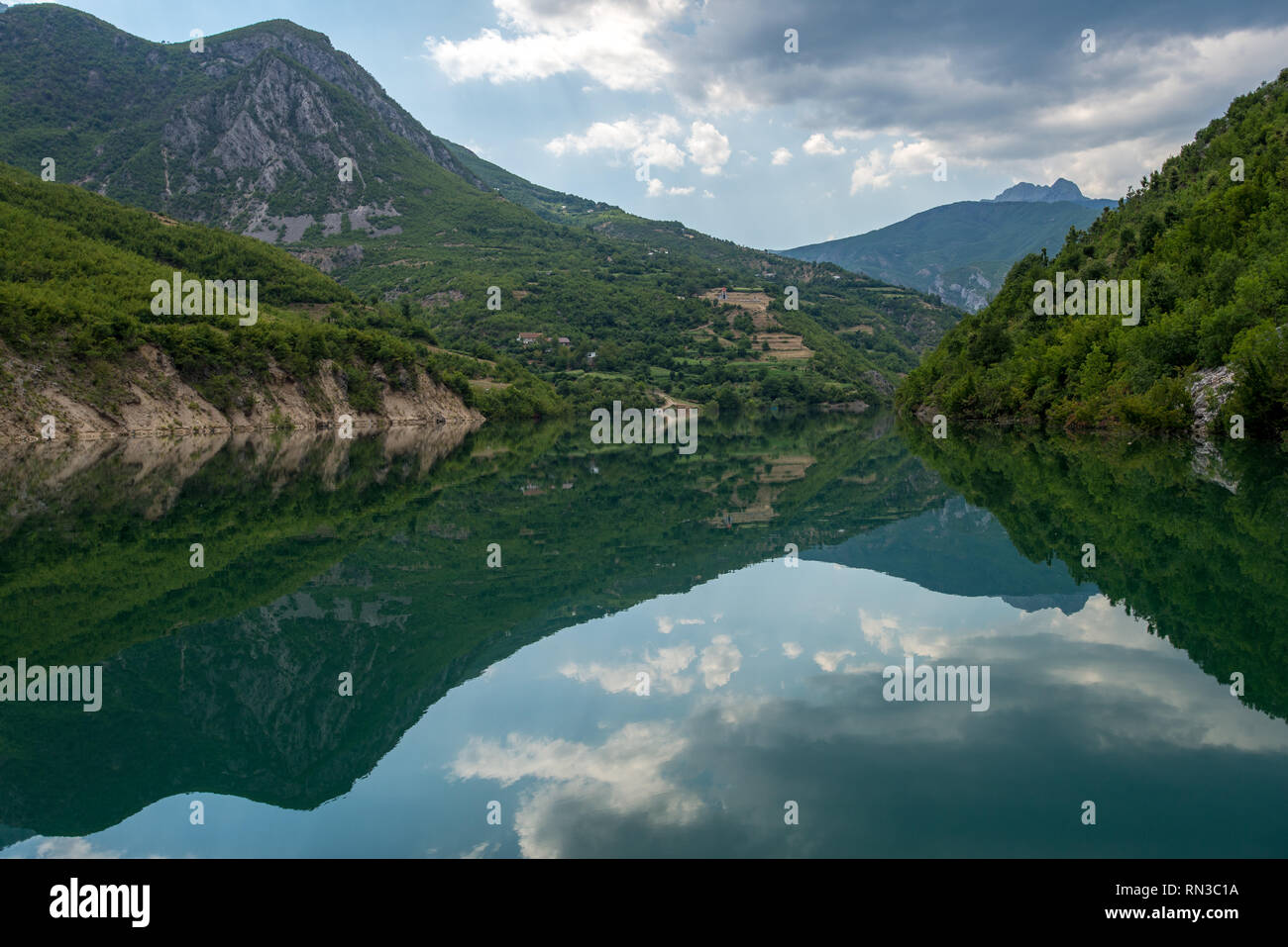 Las montañas reflejando en el lago Komani, Albania. Cielo azul y las nubes. Foto de stock
