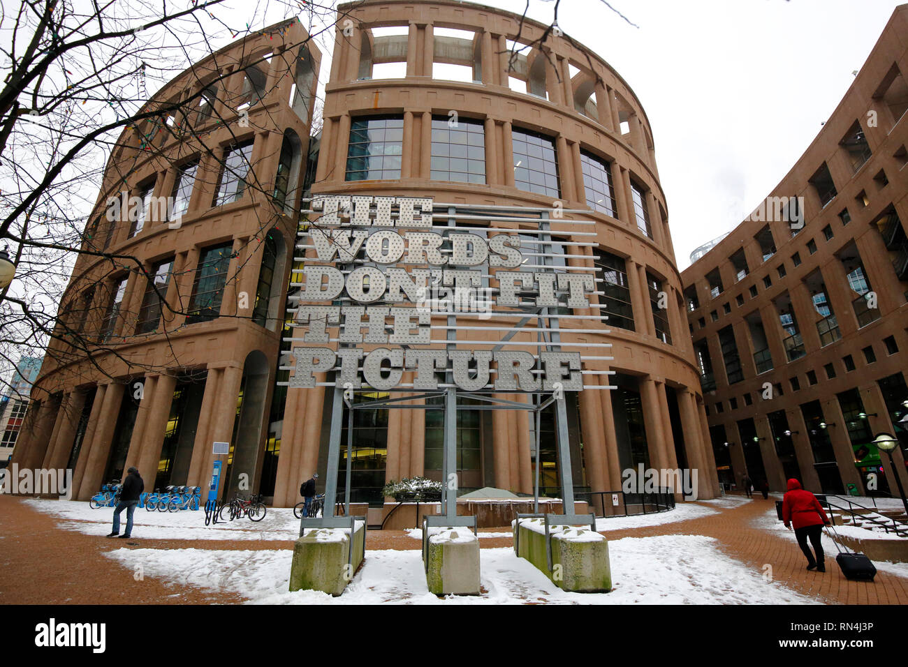 Personas que pasan por el arte público 'Las palabras no encajan en el cuadro' fuera de la Biblioteca Central de Vancouver, Vancouver, Columbia Británica, Canadá Foto de stock