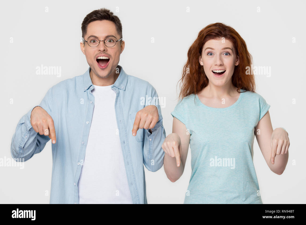 Sorprendido feliz pareja señalando con el dedo a continuación indicando una increíble oferta de venta Foto de stock