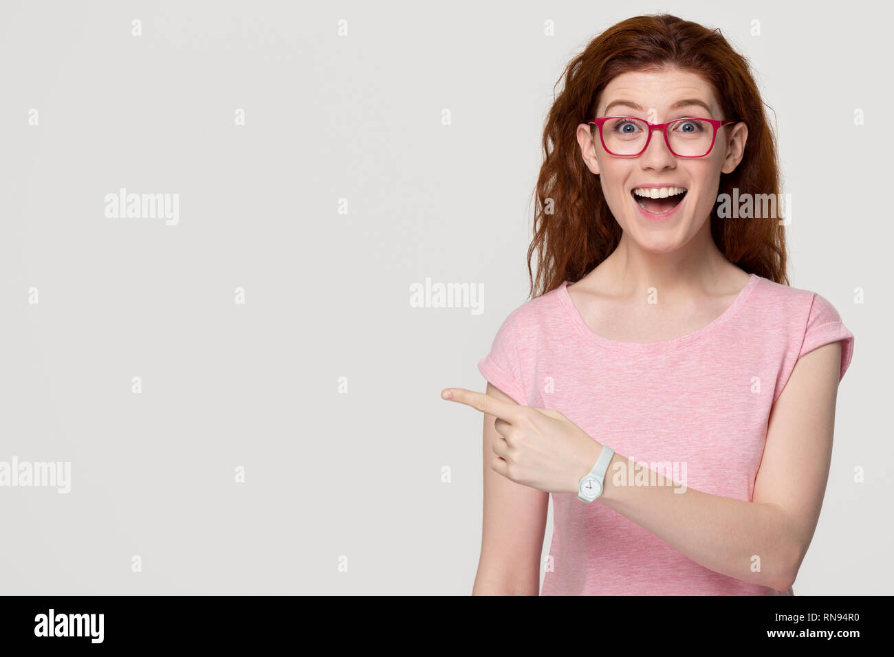 Emocionada feliz pelirroja mujer cliente dedo señalador en espacio de copia Foto de stock