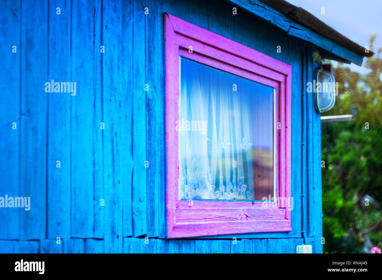 Concepto de diseño minimalista: Vivid púrpura del bastidor de la ventana, una luz en la pared azul de tablones de madera. Las montañas reflexión en vidrio, cortina blanca. Aleros de techo. Foto de stock