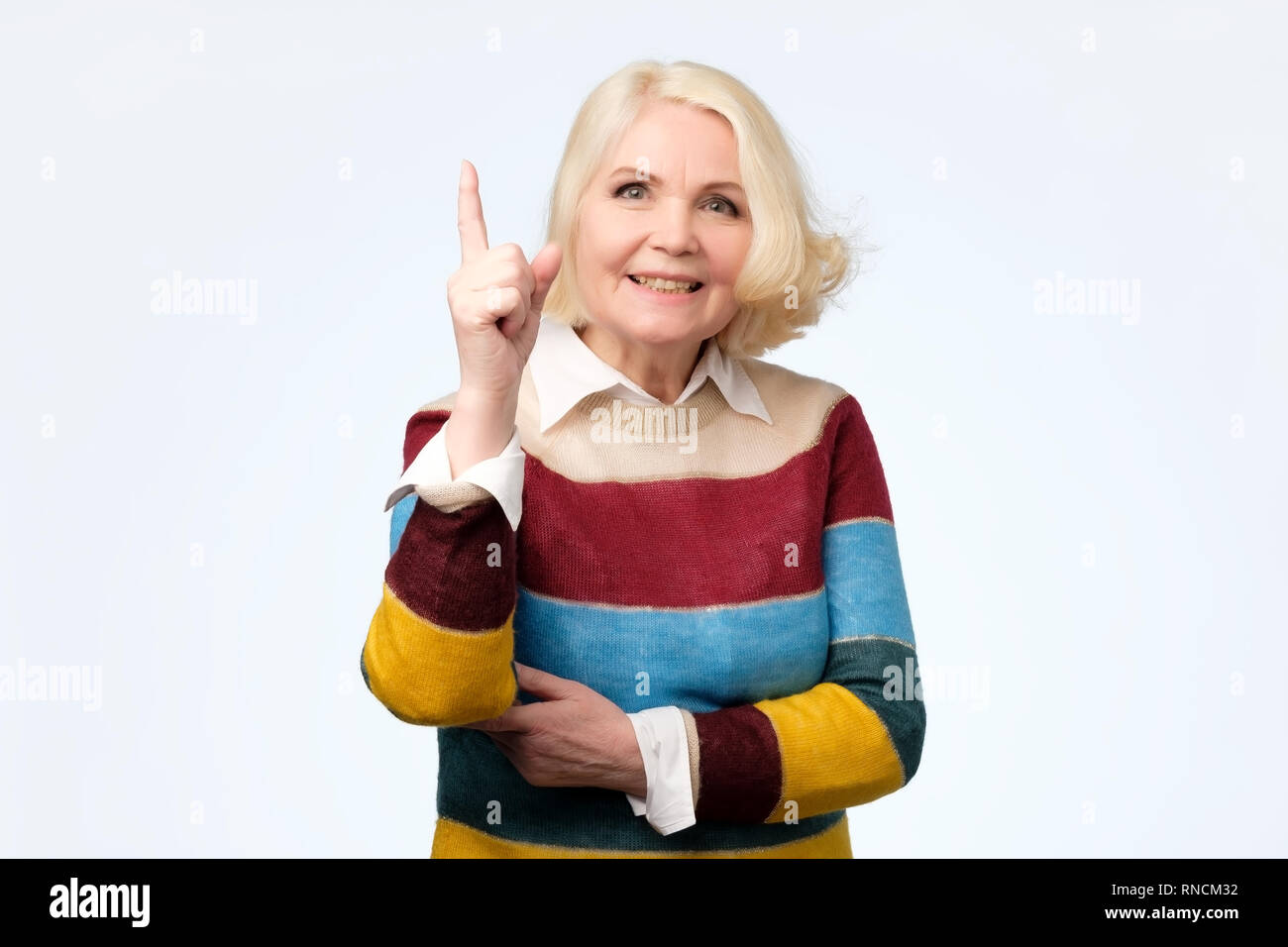 Abuela expresivo emocional con el dedo índice apuntando hacia arriba Foto de stock
