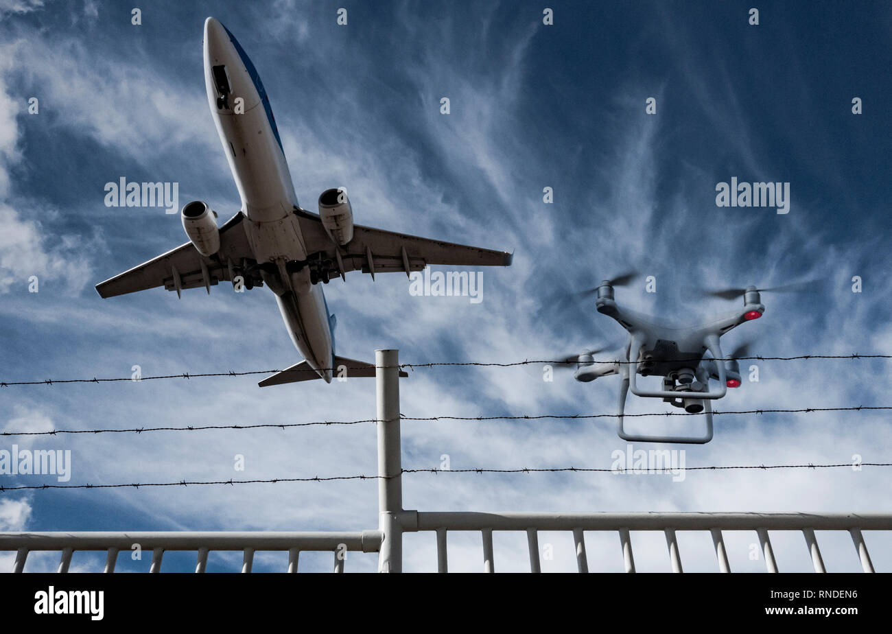 Drone volando sobre airport vallado perimetral como avión despega. Foto de stock