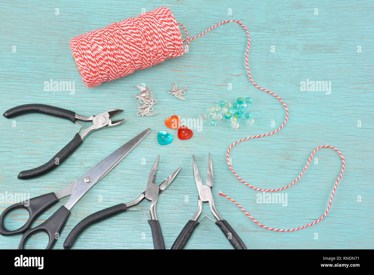 Suministros para hacer pulseras de marzo como una madeja con cordón rojo y blanco,pinzas,ave,y beeds charms Fotografía de stock - Alamy