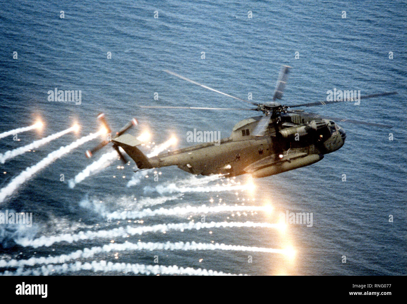 Un aire-aire Vista lateral derecha de un semental de tipo CH-53D Mar helicóptero arrojando bengalas, cerca de la Estación Aérea Naval de Patuxent River, Maryland, el helicóptero se va a través de una evaluación de la UN/ALC-39 contramedidas sistema dispensador, utilizado para proporcionar protección contra las armas guiadas. Foto de stock