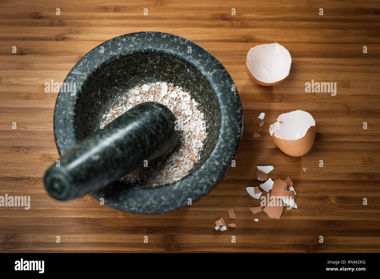 Pollo doméstico. Molienda de cáscaras de huevo cocido en un mortero. Foto de stock