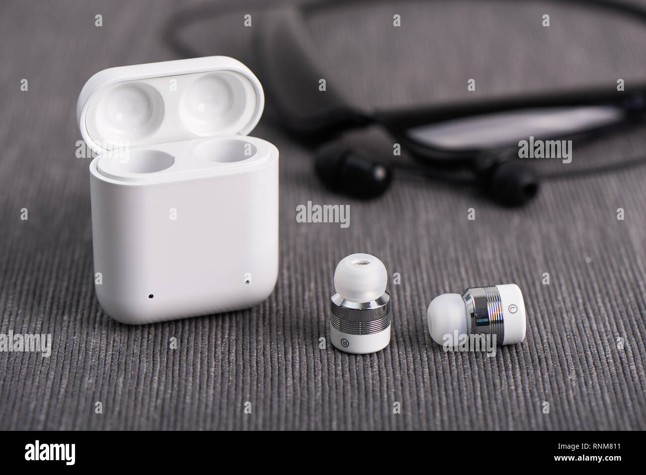 Auriculares Bluetooth inalámbricos inalámbrica con cargo caso sobre un fondo de auricular tipo nuca Foto de stock
