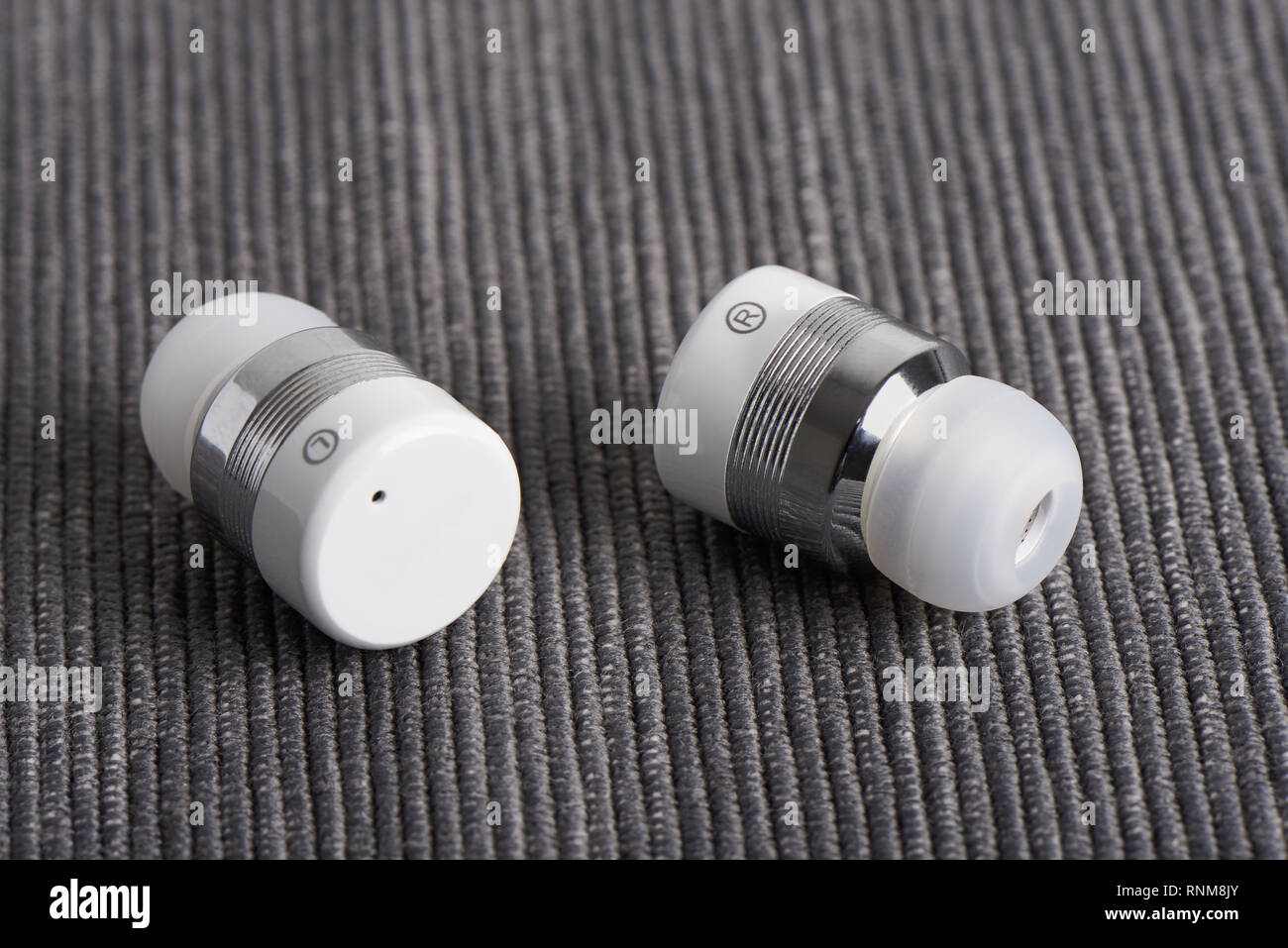 Close-up de auriculares estéreo Bluetooth inalámbricos inalámbrica sobre un fondo de tela Foto de stock