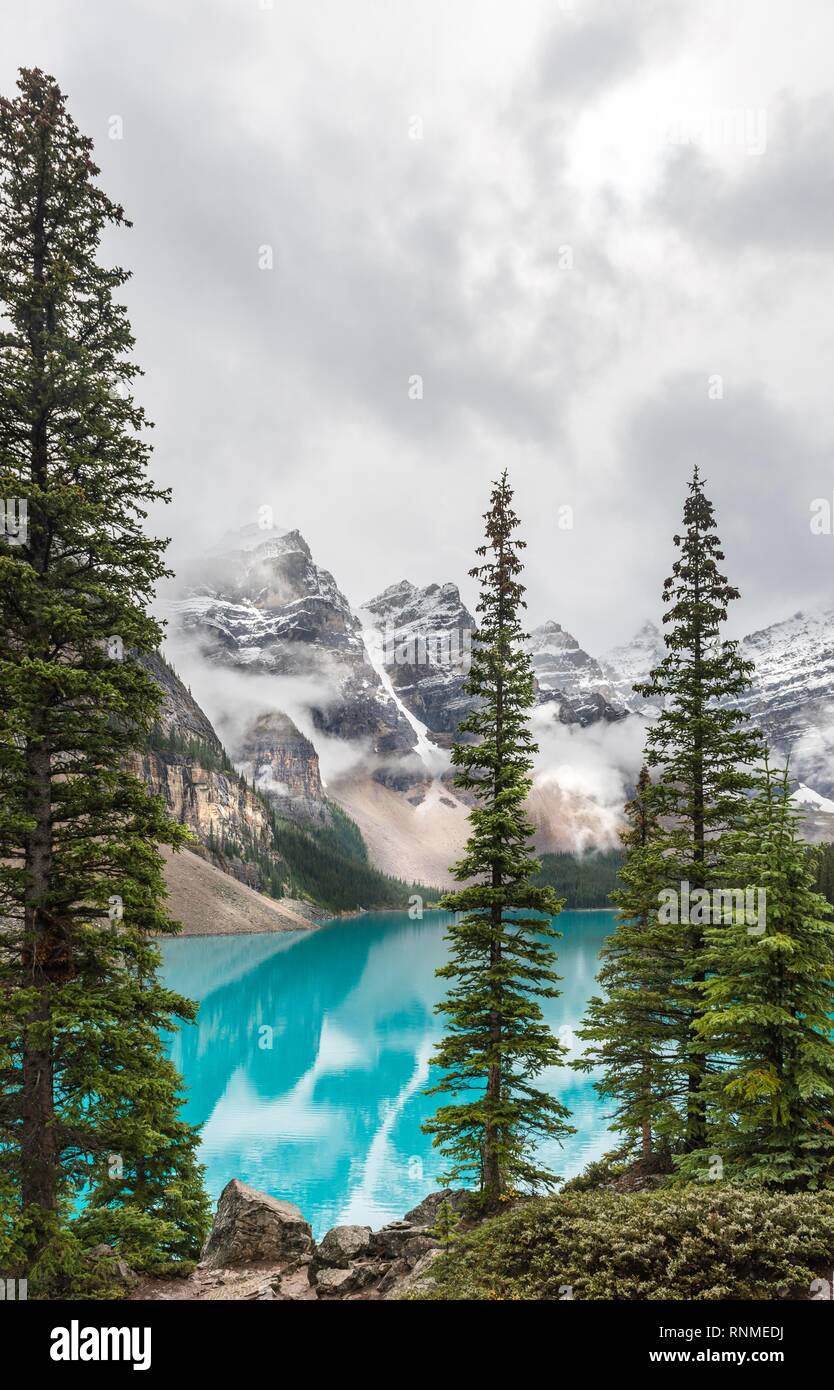 Las nubes colgando entre los picos de la montaña, la reflexión en turquesa del lago glacial, el Lago Moraine, el Valle de los Diez Picos, Montañas Rocosas, Banff unidas Foto de stock