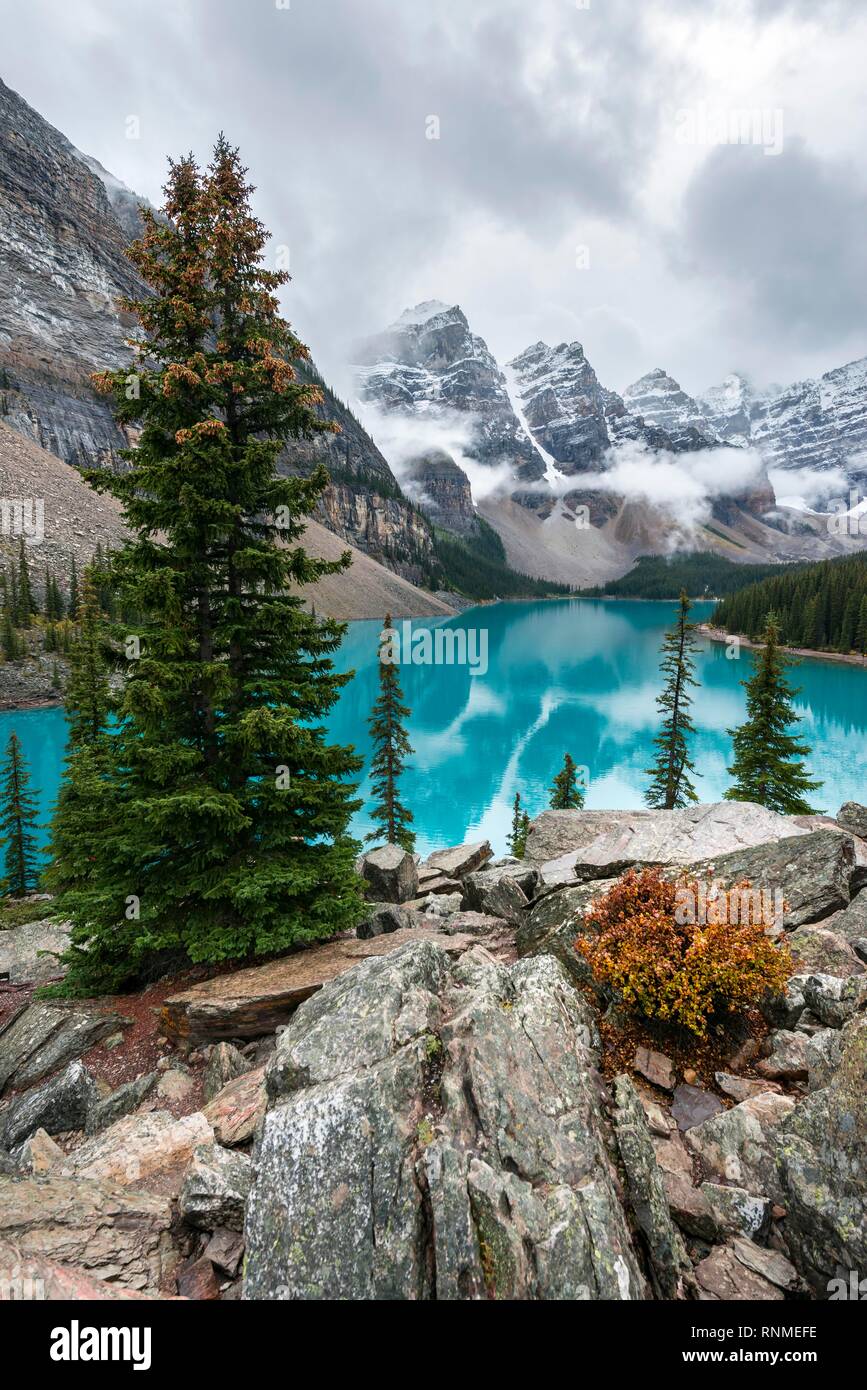Las nubes colgando entre los picos de la montaña, la reflexión en turquesa del lago glacial, el Lago Moraine, el Valle de los Diez Picos, Montañas Rocosas, Banff unidas Foto de stock