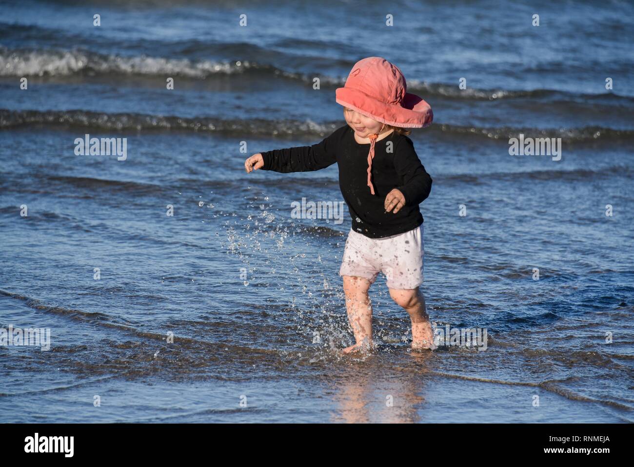 Chica corriendo en el agua en la playa, Puerto Madryn, Argentina Foto de stock