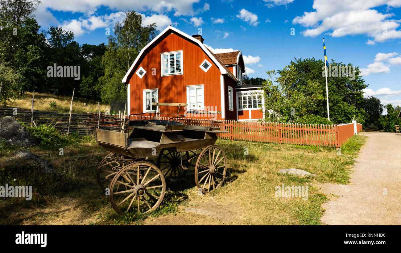 Carro antiguo en frente de la casa de labranza de madera roja sobre Katthult corral en Lönneberga, Schweden, Michel, Astrid Lindgren Foto de stock