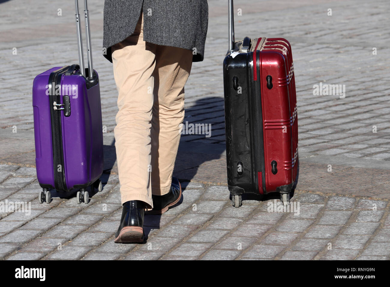 El hombre elegante con dos maletas sobre caminando por una calle. Las piernas masculinas y equipaje en la calle empedrada, vista posterior. Concepto de viaje, prisas Fotografía de stock - Alamy