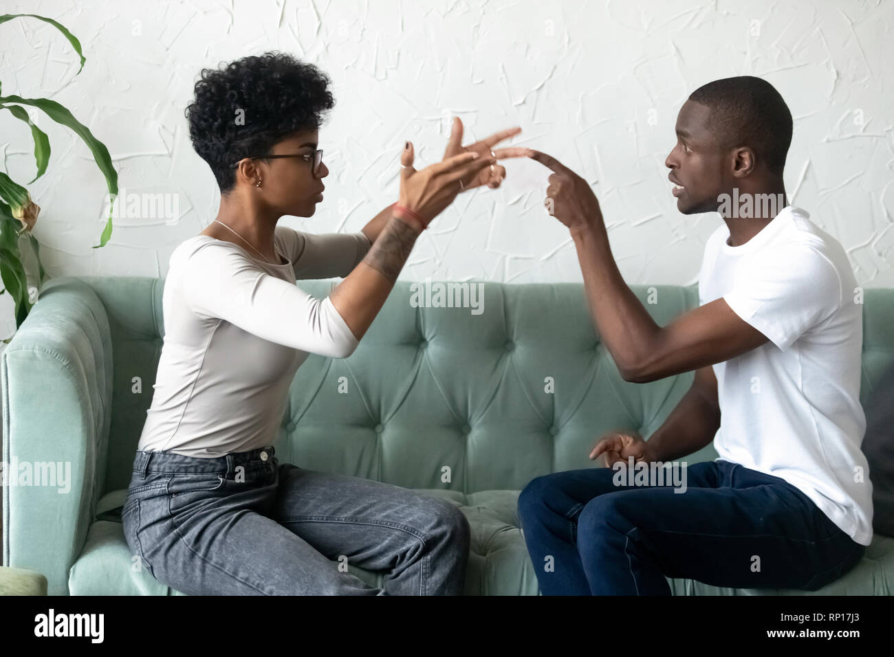 Pareja de africanos negros peleaban sentado en sofá Foto de stock