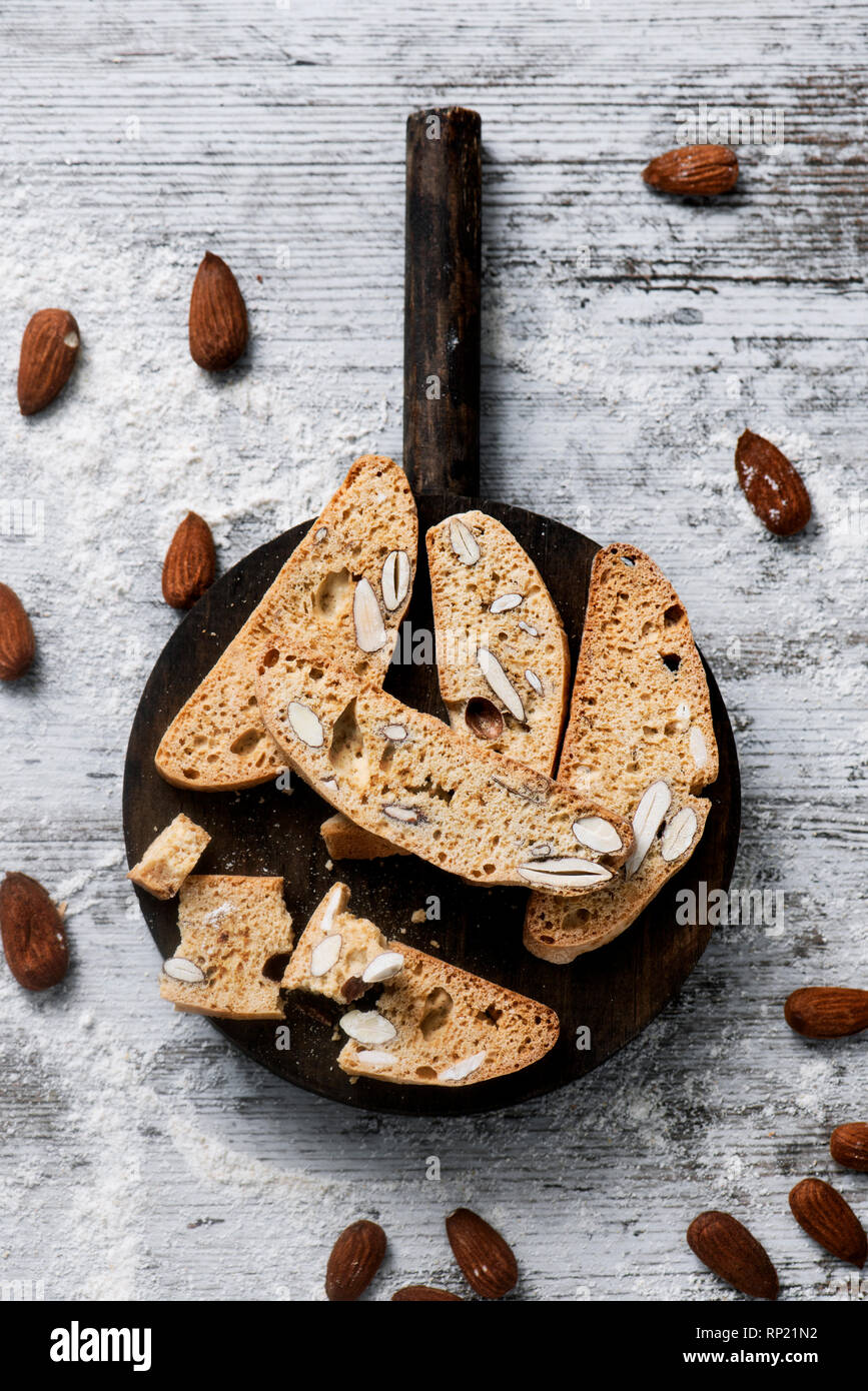 Un alto ángulo de visualización de algunos carquinyolis, pasteles típicos de Cataluña, España, hecha con almendras, en una bandeja de madera redondo, colocado sobre un rústico de madera blanca Foto de stock