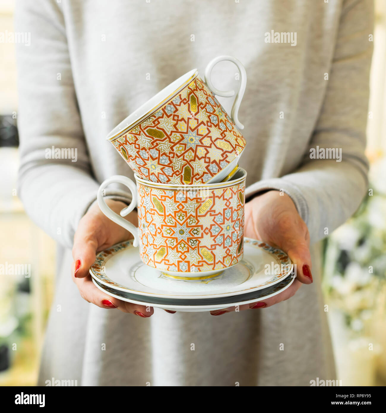 Elegantes tazas de té o café y platillos en manos de las mujeres. Mujer  sostiene un plato de cerámica Fotografía de stock - Alamy
