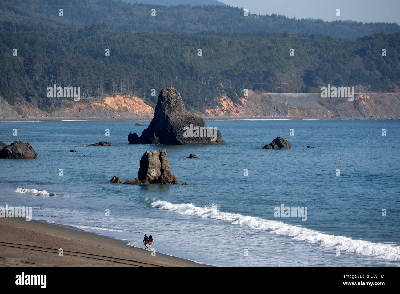 Una pareja (hombre y mujer) caminando en la escarpada costa del Océano Pacífico cerca de Battle Rock Wayside Park, Puerto Orford, Oregon, Estados Unidos Foto de stock