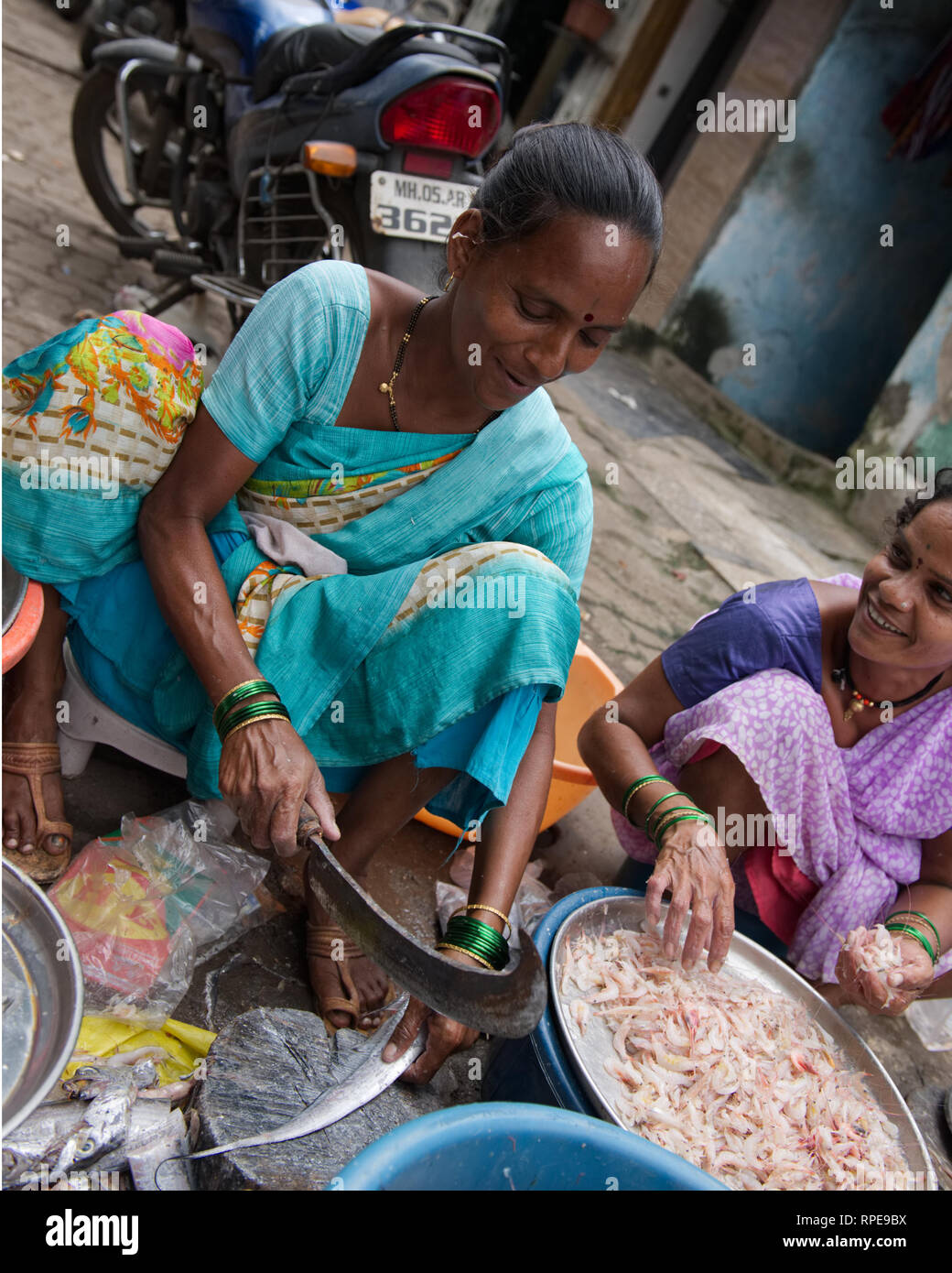 Las mujeres expertamente preparar pescado para su venta en el mercado de pescado de Mumbai. Hábilmente utilizando un machete Tipo de cuchilla. Foto de stock