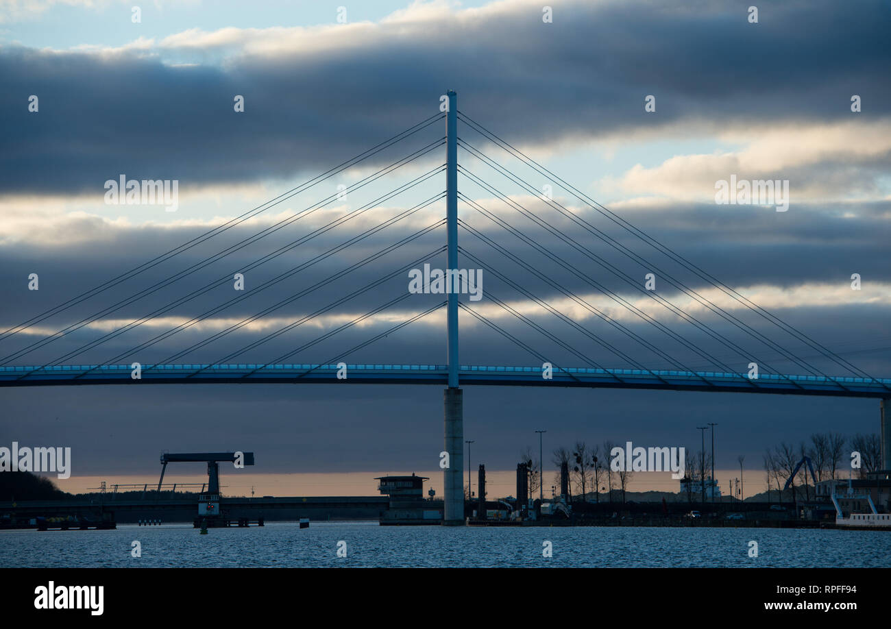Stralsund, Alemania. 22 Feb, 2019. El sol naciente en la parte delantera de la 'Rügenbrücke' baña el cielo, en el puerto de una luz cálida. Crédito: Stefan Sauer/dpa-Zentralbild/dpa/Alamy Live News Foto de stock