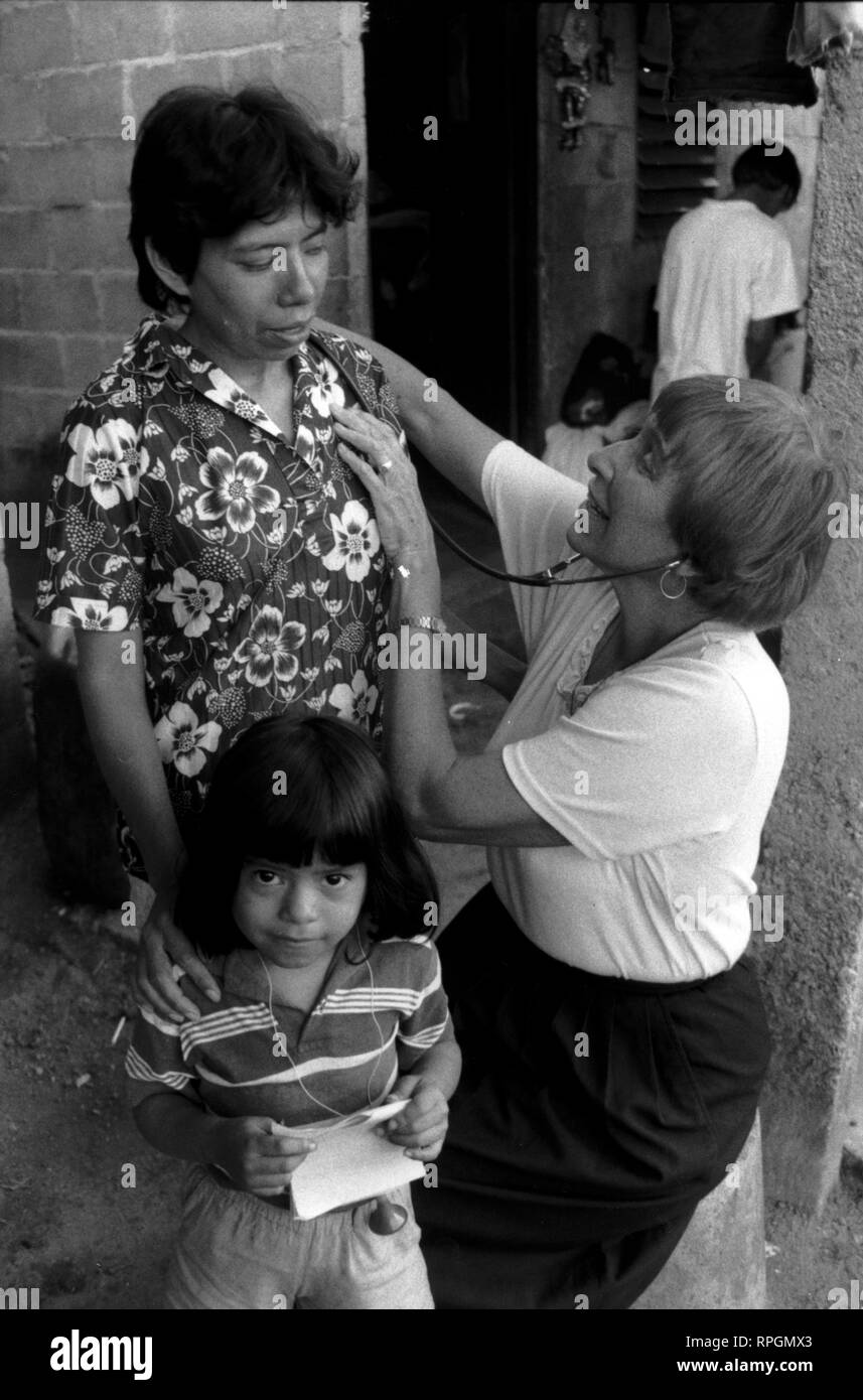 624 - SIDA/Doctor Hermana Mary Annel de Maryknoll examina el SIDA víctima Flor de Maria Flores. 5-año-viejo Iris, primer plano, también tiene SIDA. Equipo diocesano de SIDA. San Salvador, El Salvador © Sean Sprague Foto de stock