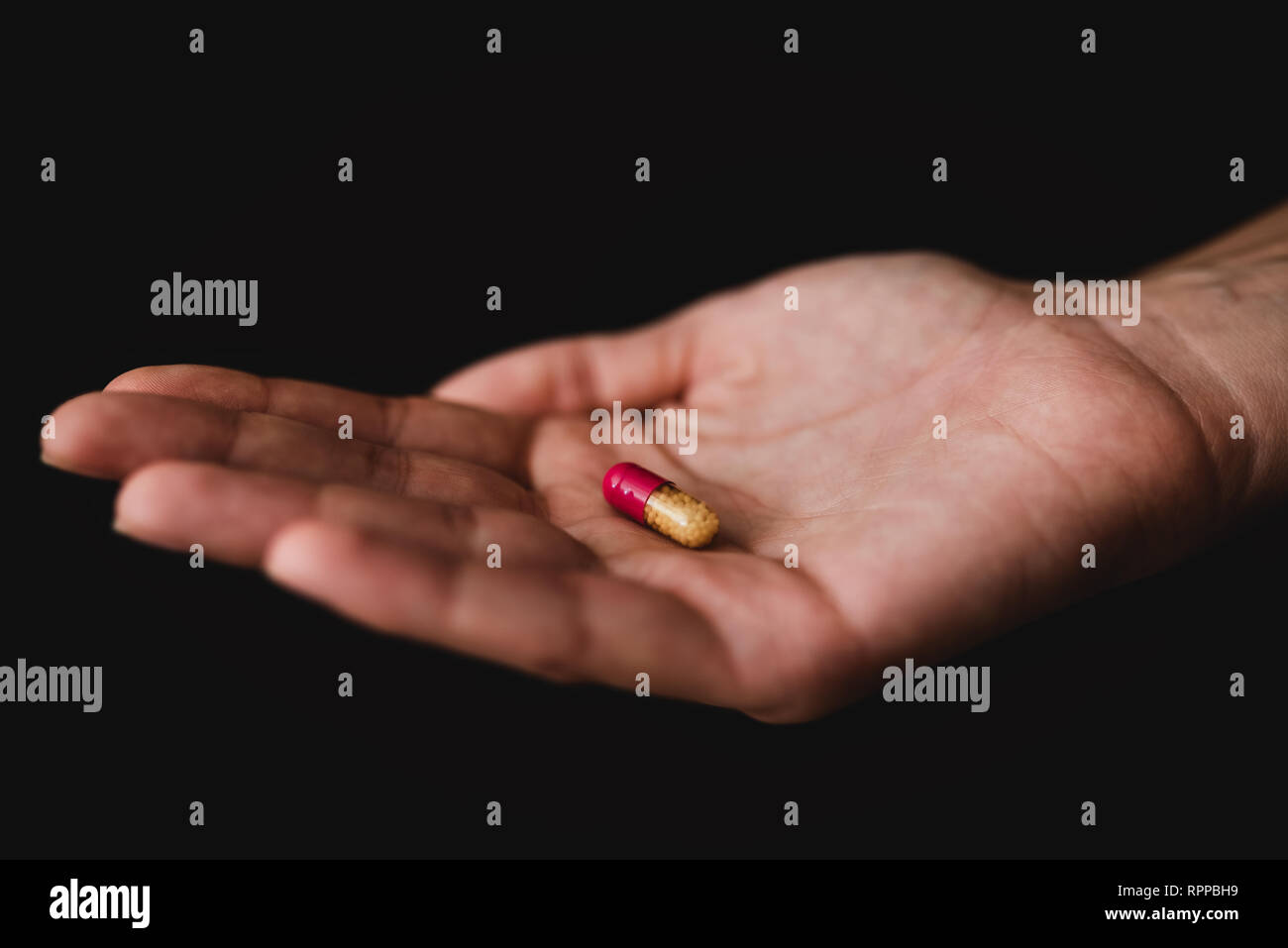 Medicina píldoras en mano, aislado sobre fondo negro. Farmacia y Medicamentos Foto de stock