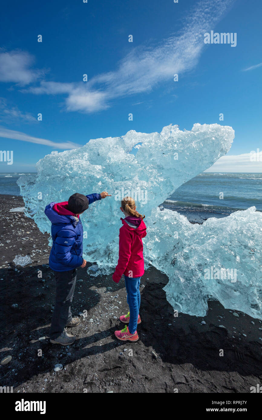 Las personas examinando Breidamerkursandur icebergs en la playa de arena negra, debajo de Jokulsarlon. Sudhurland, sudeste de Islandia. Foto de stock