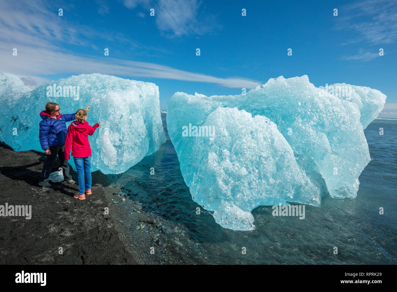 Las personas examinando Breidamerkursandur icebergs en la playa de arena negra, debajo de Jokulsarlon. Sudhurland, sudeste de Islandia. Foto de stock